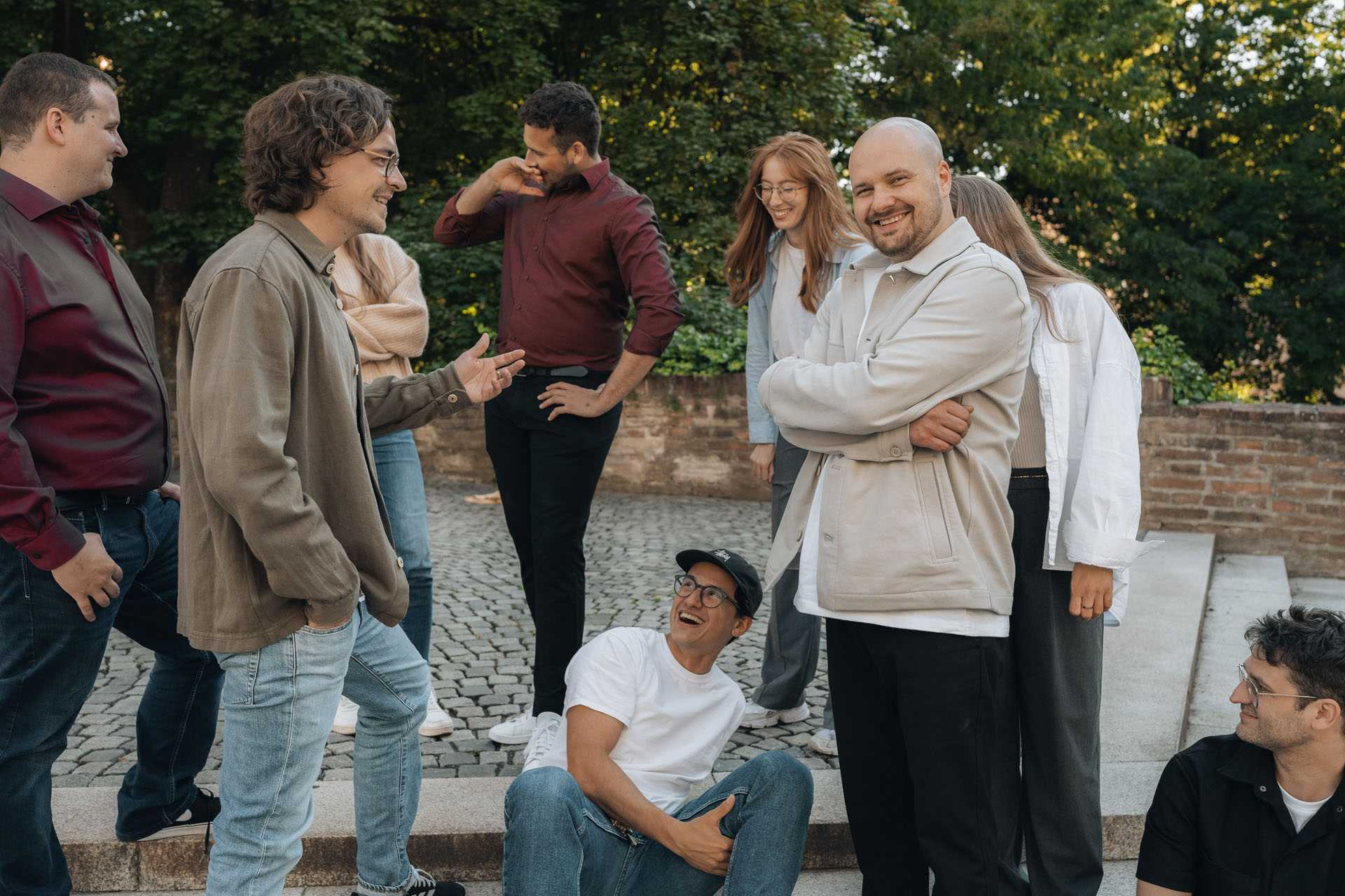 Das typedigital Team sitzt bei einem Park in Augsburg. Sie lachen.