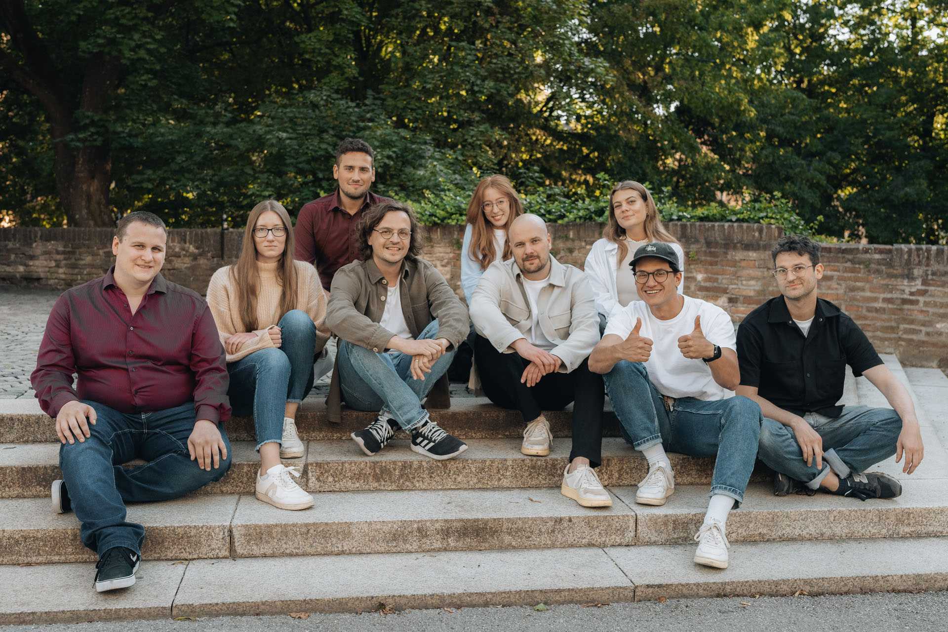 Das typedigital Team sitzt bei einem Park in Augsburg. Daumen hoch.