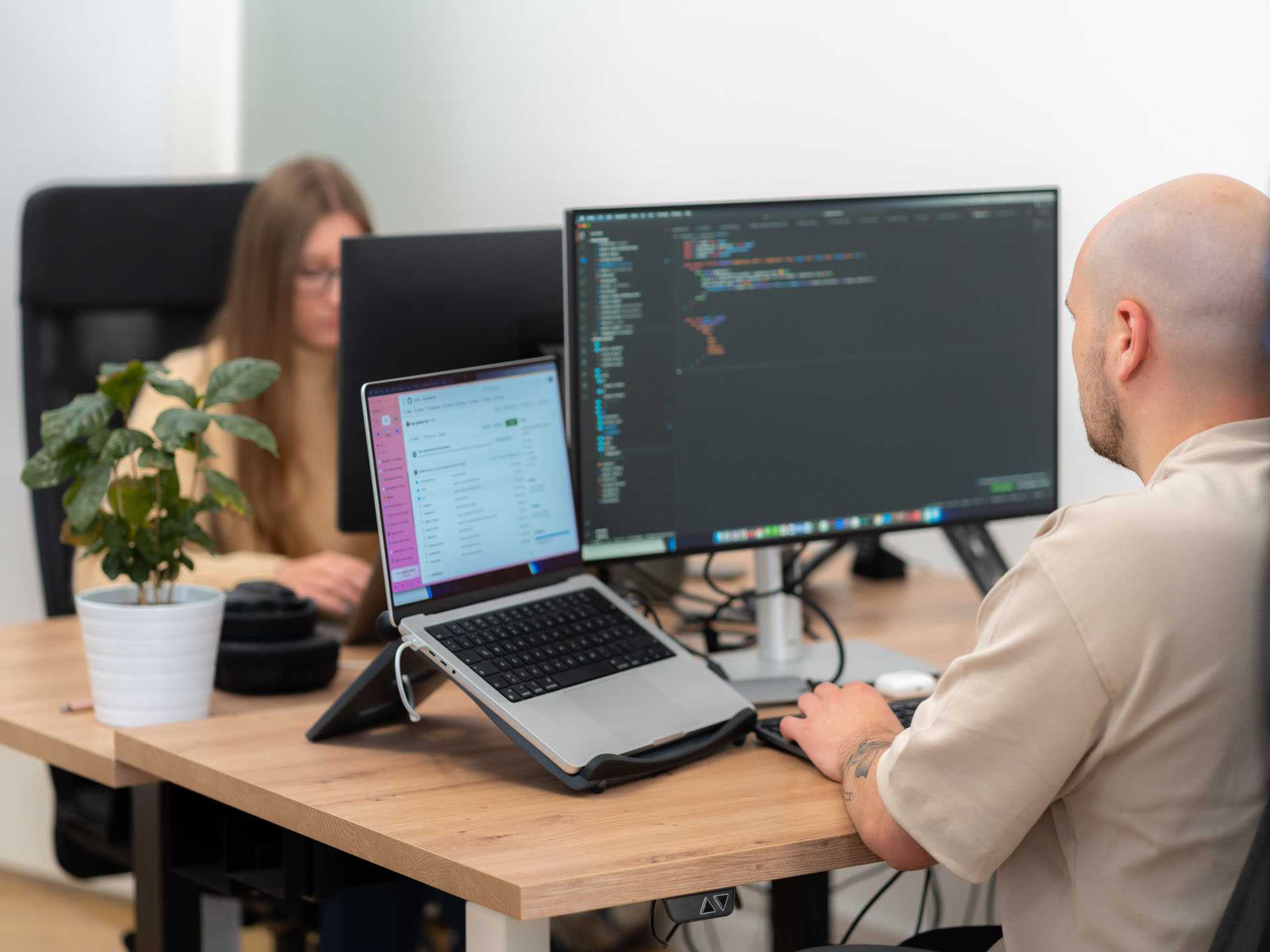 Zwei Programmierer sitzen auf ihrem Platz und arbeiten am PC.